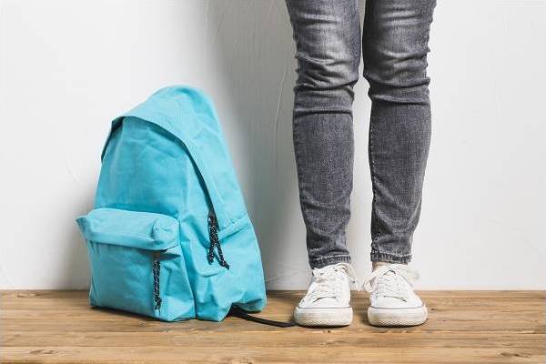 personne sans visage debout a cote du cartable sur la table en bois